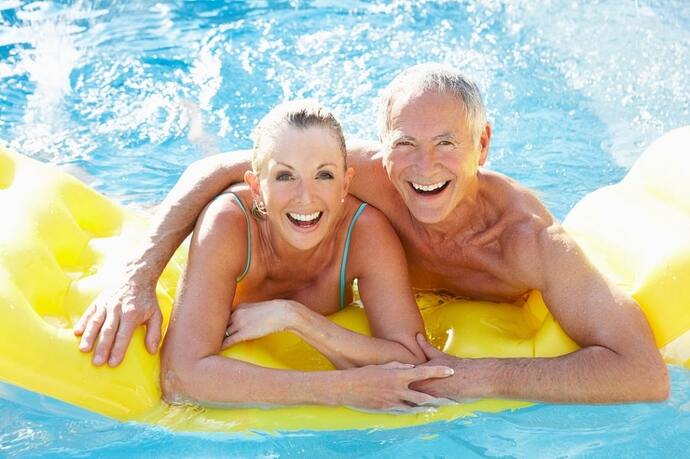 A group of active adults enjoying a resort style pool in a 55+ community